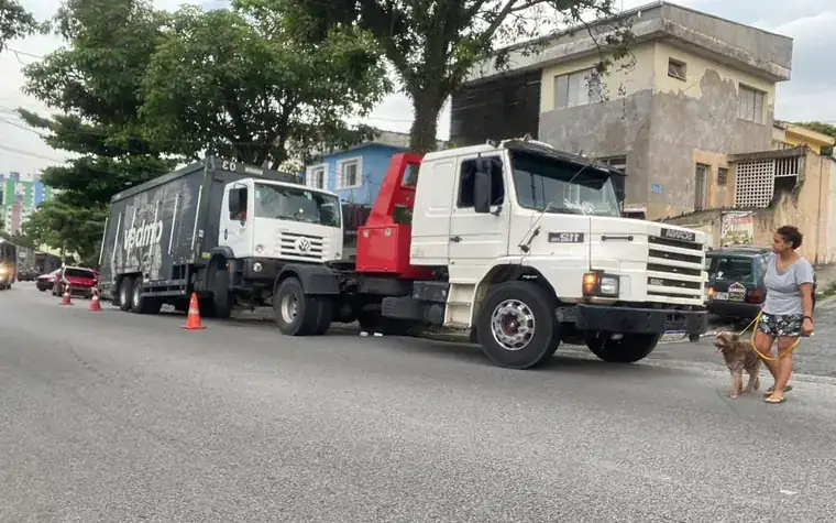 Guincho lança rebocando um caminhão baú em via urbana sinalizada com cones