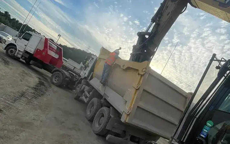 Plataforma removendo escavadeira e caçamba em canteiro de obra